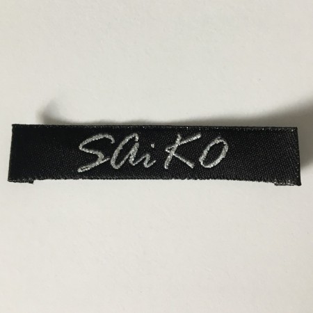 Этикетка жаккардовая вышитая Saiko12мм черная с серебром заказная (1000 штук)